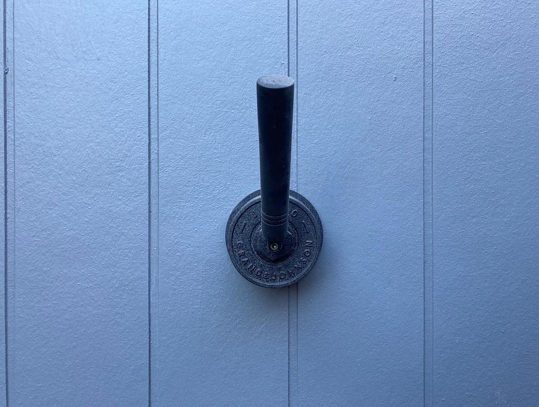 Detail baterie nástěnné černé nerezové sprchy JEE-O soho umístěné na bílé dřevěné stěně